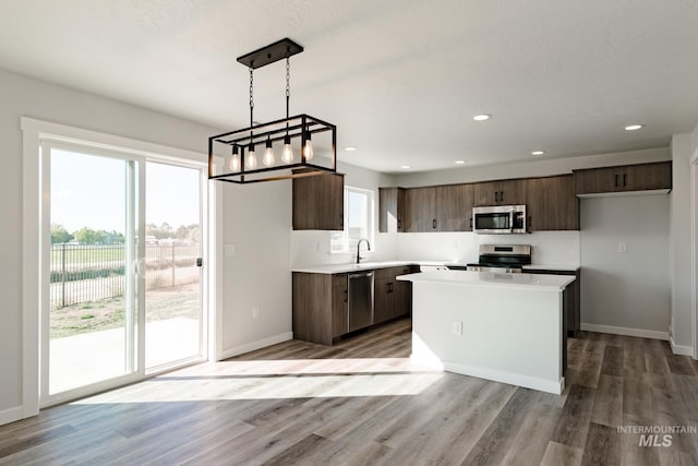 kitchen with stainless steel appliances, light countertops, light wood-type flooring, backsplash, and a chandelier