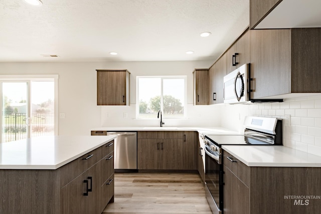 kitchen with a sink, light countertops, light wood finished floors, and stainless steel appliances