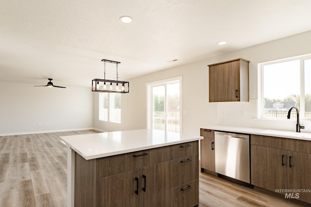 kitchen with light wood-style flooring, a sink, stainless steel dishwasher, light countertops, and decorative backsplash