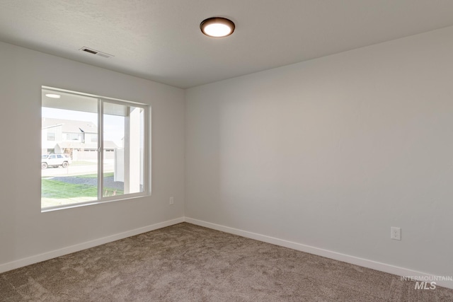 carpeted empty room featuring baseboards and visible vents