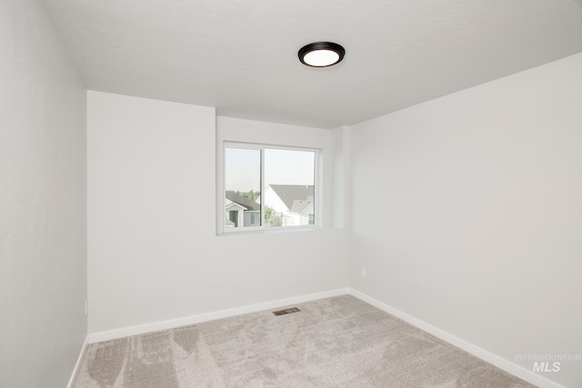 spare room with baseboards, visible vents, and carpet flooring