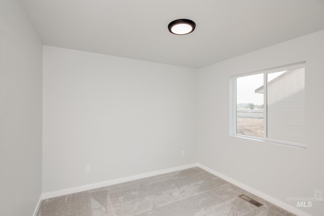 spare room with light colored carpet, visible vents, and baseboards