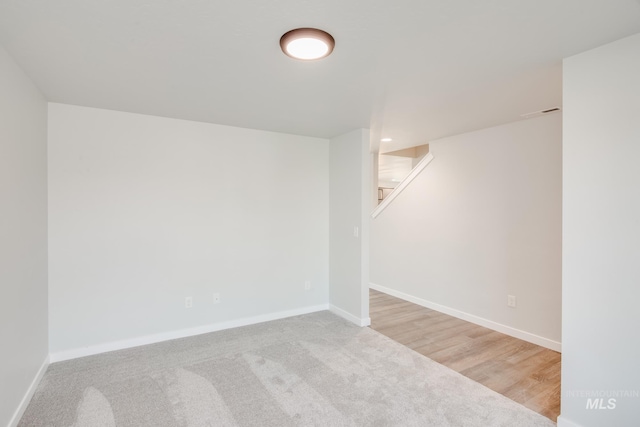 below grade area with stairs, baseboards, and light colored carpet