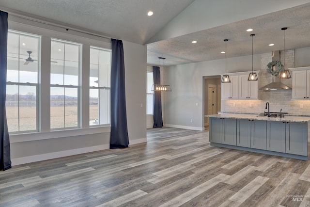 kitchen with light wood-type flooring, tasteful backsplash, a textured ceiling, and vaulted ceiling