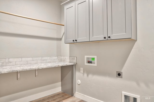 washroom with light wood finished floors, baseboards, hookup for a washing machine, cabinet space, and electric dryer hookup