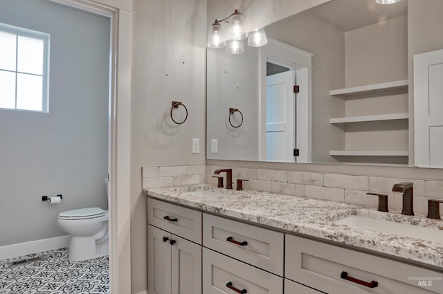 full bathroom with a sink, baseboards, toilet, and double vanity