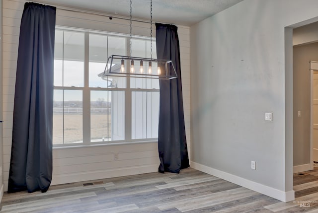 spare room with visible vents, baseboards, and wood finished floors