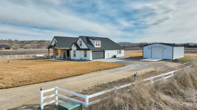 view of front of house featuring fence, a front lawn, an outdoor structure, a garage, and dirt driveway