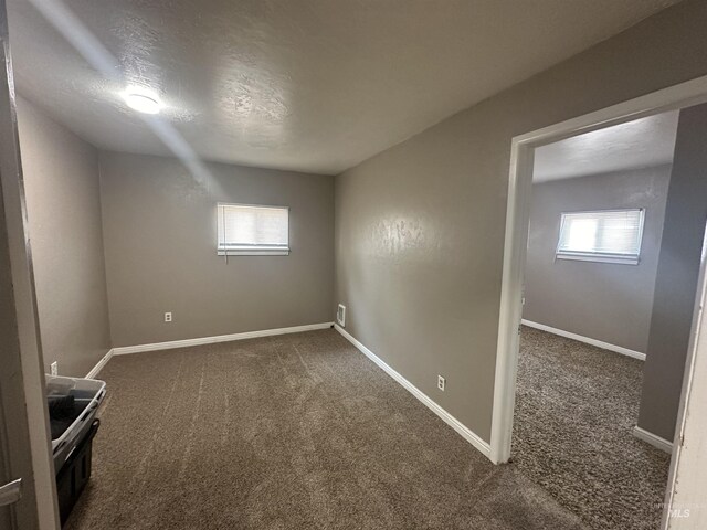 unfurnished room featuring dark carpet