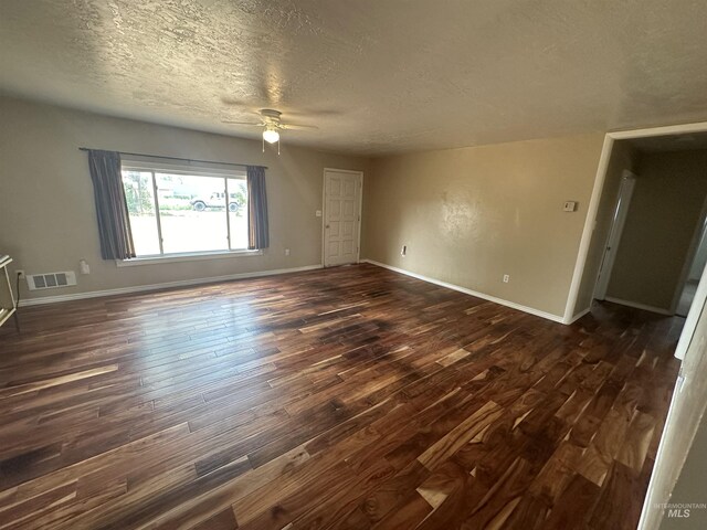 spare room with dark hardwood / wood-style floors, ceiling fan, and a textured ceiling