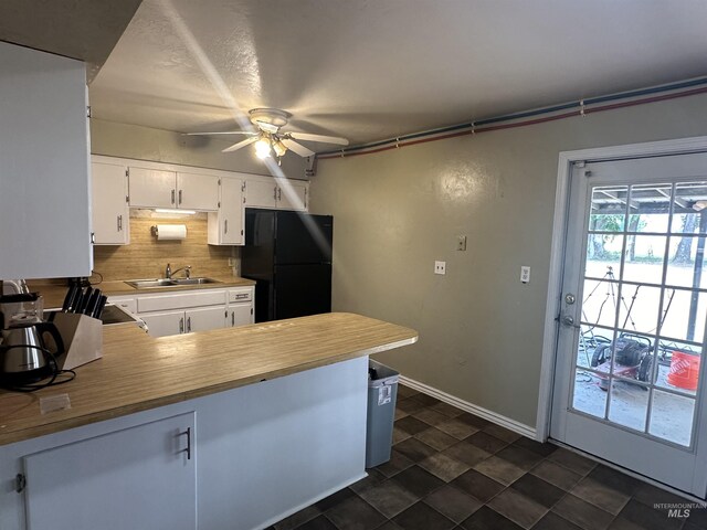 kitchen featuring dark tile patterned floors, sink, decorative backsplash, ceiling fan, and black fridge