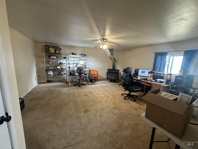 office with ceiling fan, carpet flooring, and a wood stove