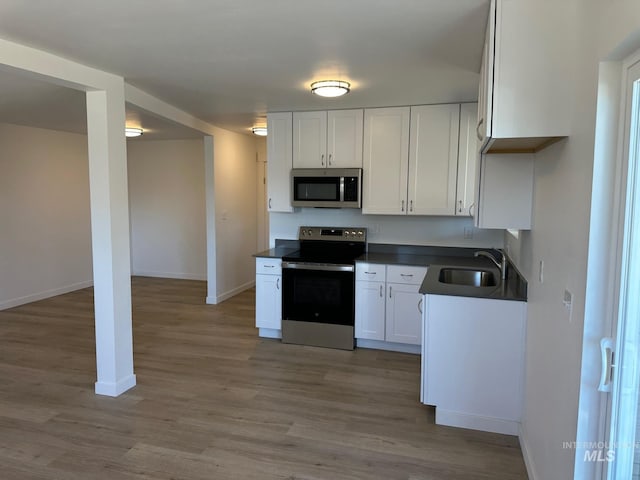 10331 W Utahna, Boise, ID 83714 - kitchen with appliances with stainless steel finishes, dark countertops, baseboards, white cabinetry, and wood finished floors