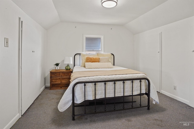 bedroom featuring vaulted ceiling, dark carpet, and baseboards