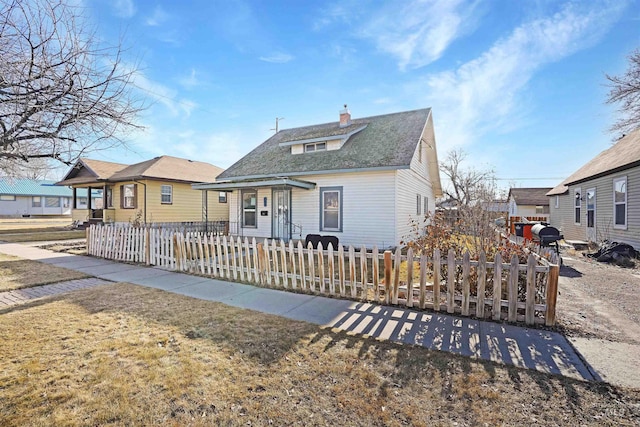 bungalow featuring a fenced front yard, a shingled roof, a chimney, and a front lawn