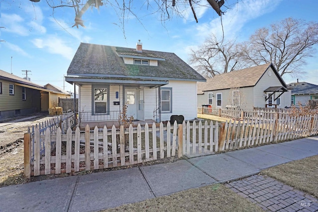 bungalow-style house featuring covered porch, a fenced front yard, and a chimney