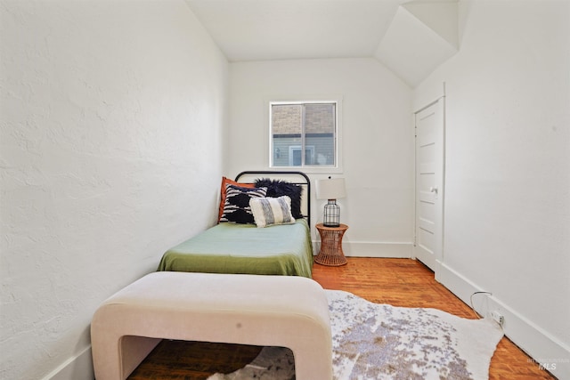 bedroom with a textured wall, baseboards, and wood finished floors