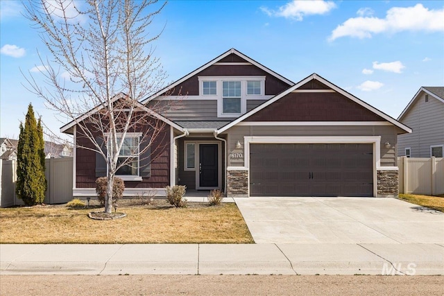 craftsman house with stone siding, fence, concrete driveway, a front yard, and an attached garage