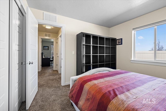 carpeted bedroom with visible vents, baseboards, a textured ceiling, and a closet