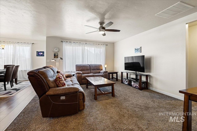 living area featuring baseboards, visible vents, a textured ceiling, and ceiling fan