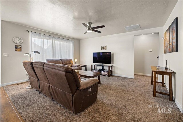 living room with visible vents, baseboards, ceiling fan, carpet flooring, and a textured ceiling