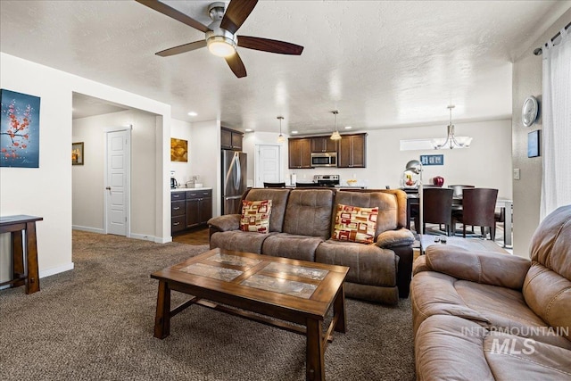 living area featuring ceiling fan with notable chandelier, baseboards, dark colored carpet, and a textured ceiling