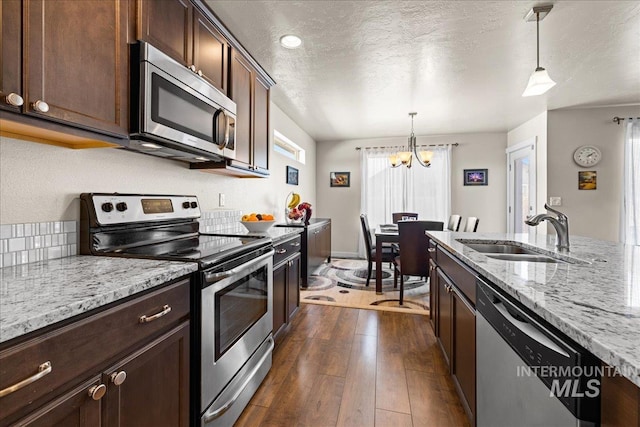 kitchen with dark wood-type flooring, pendant lighting, a sink, a textured ceiling, and stainless steel appliances