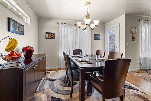 dining room featuring baseboards, a chandelier, and light wood finished floors