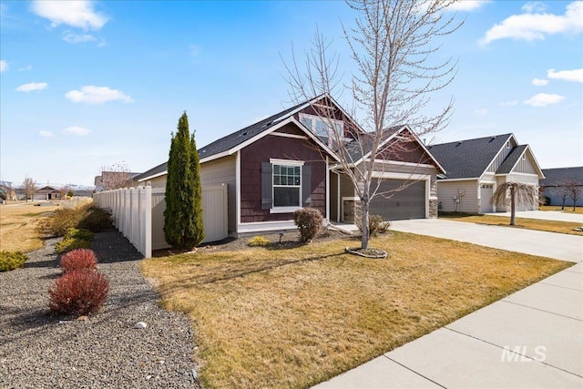 view of front of property featuring a front lawn, concrete driveway, an attached garage, and fence