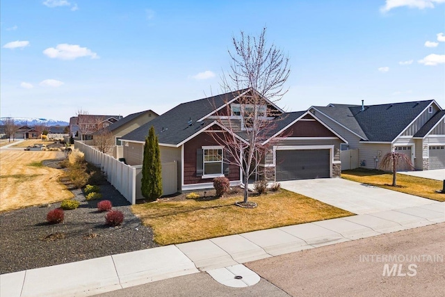 view of front of house with an attached garage, a front lawn, fence, stone siding, and driveway