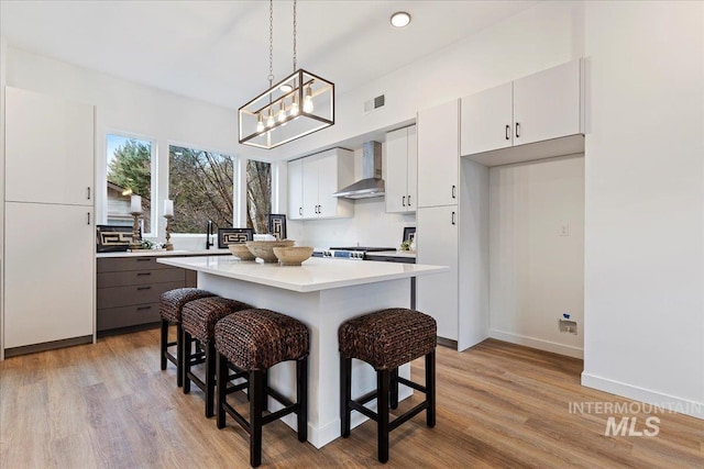 2031 S Makar Ln, Boise, ID 83706 - kitchen with wall chimney range hood, light countertops, a kitchen breakfast bar, and light wood-style floors