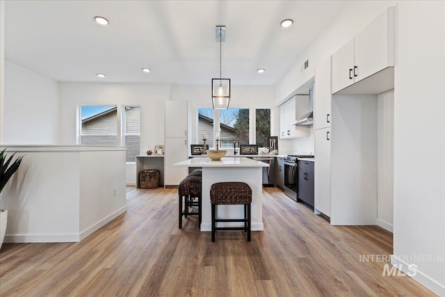 2031 S Makar Ln, Boise, ID 83706 - kitchen with stainless steel range with gas stovetop, white cabinetry, a breakfast bar area, light wood-style flooring, and recessed lighting