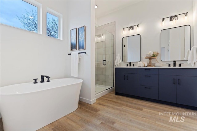 2031 S Makar Ln, Boise, ID 83706 - full bathroom featuring a freestanding tub, double vanity, a stall shower, wood finished floors, and baseboards