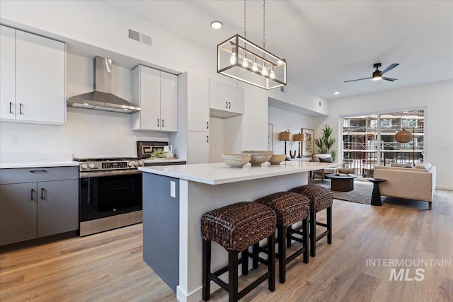 2031 S Makar Ln, Boise, ID 83706 - kitchen with wall chimney range hood, stainless steel gas range, a kitchen breakfast bar, light wood-style flooring, and open floor plan