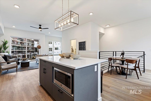 2031 S Makar Ln, Boise, ID 83706 - kitchen with stainless steel microwave, open floor plan, light wood-style floors, ceiling fan, and pendant lighting