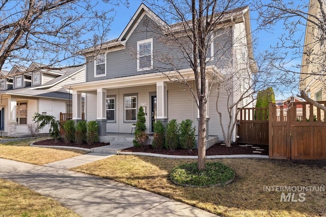 american foursquare style home with a porch and fence