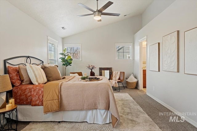 carpeted bedroom with visible vents, ceiling fan, baseboards, lofted ceiling, and ensuite bathroom