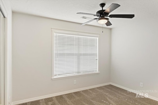 carpeted spare room featuring visible vents, baseboards, and ceiling fan