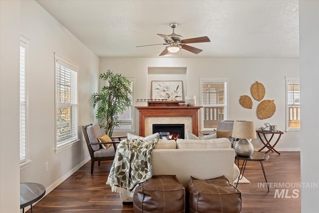 living area featuring dark wood finished floors, a glass covered fireplace, and baseboards