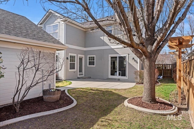 rear view of property featuring a patio area, a yard, fence, and roof with shingles