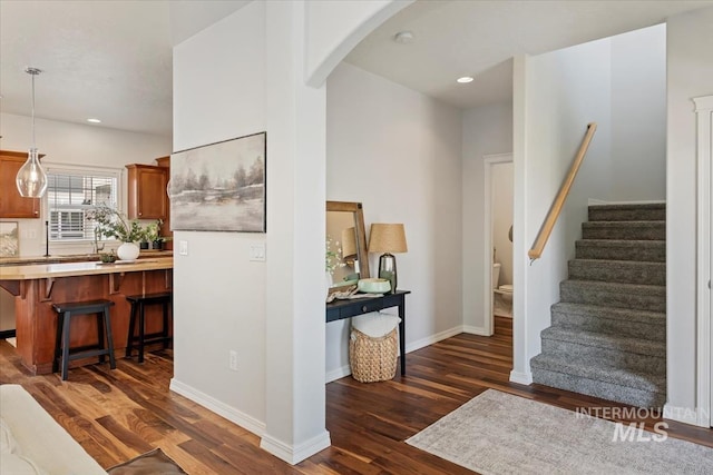 interior space featuring dark wood-style floors, recessed lighting, stairway, arched walkways, and baseboards