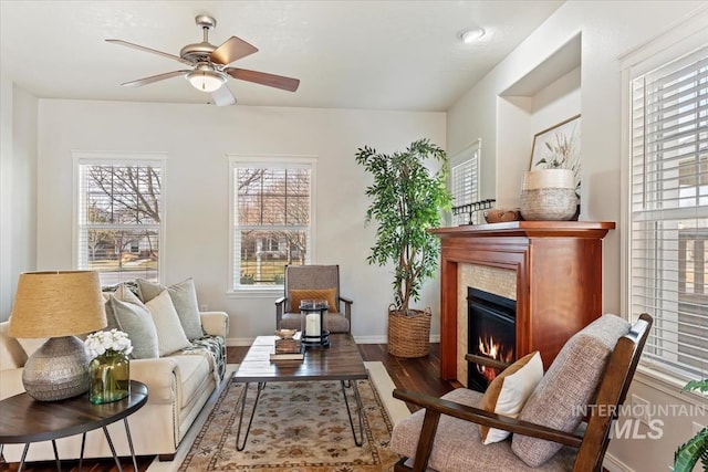 sitting room featuring a ceiling fan, wood finished floors, baseboards, and a tile fireplace