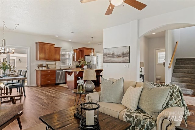 living room with dark wood-type flooring, stairway, plenty of natural light, and arched walkways