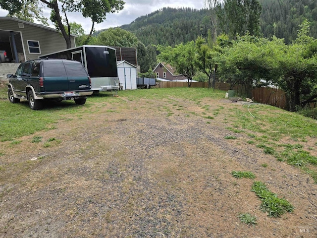 1230 Ellis Ave, Orofino, ID 83544 - view of yard with fence, a storage shed, a mountain view, an outbuilding, and a forest view