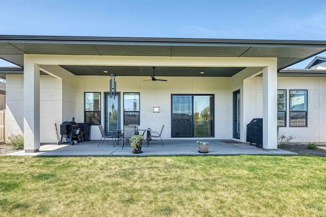 back of property with a yard, a patio, a ceiling fan, and stucco siding