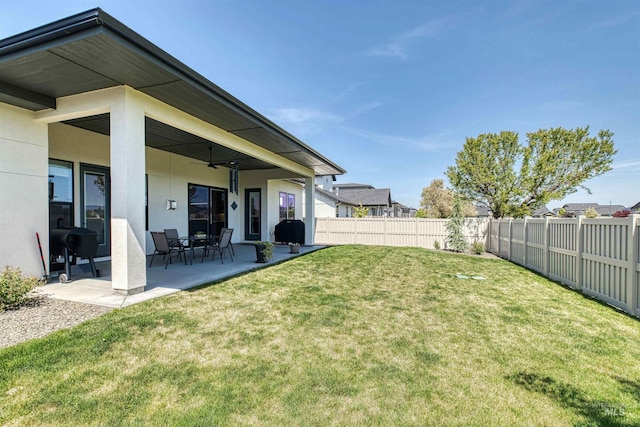 view of yard with a fenced backyard, a ceiling fan, and a patio area