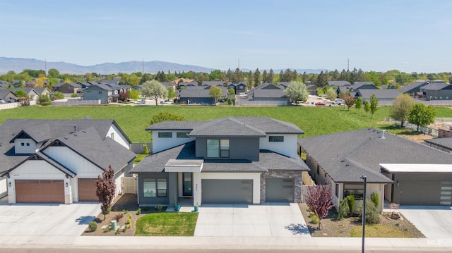 view of front facade featuring roof with shingles, a mountain view, a residential view, and concrete driveway