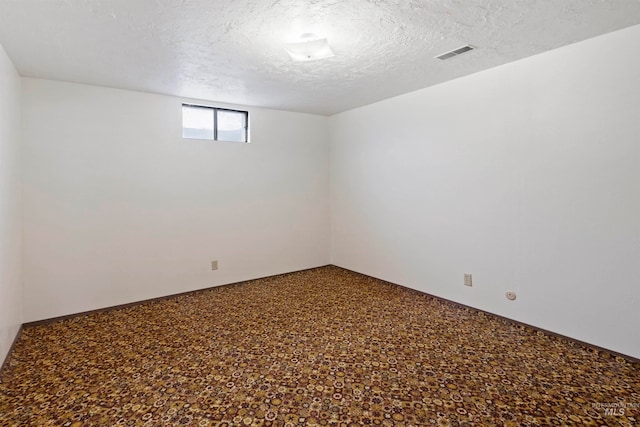 empty room featuring visible vents, carpet flooring, and a textured ceiling