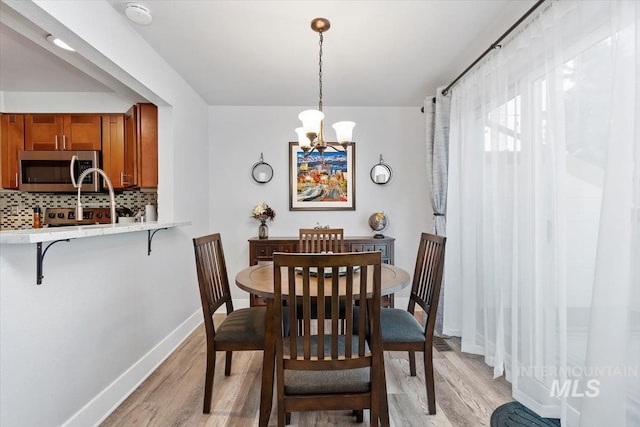 dining area featuring light wood-style floors, baseboards, and an inviting chandelier