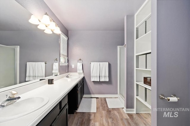 full bath with a sink, double vanity, an enclosed shower, and wood finished floors